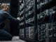 Engineer adjusting Bitcoin mining servers in a data center amid network power struggle over anti-spam proposal and disputed node support